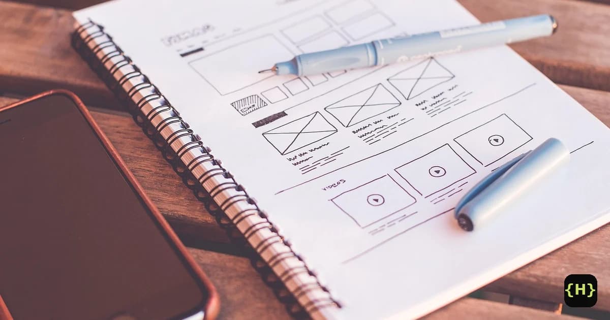 A hand-drawn website wireframe sketch on a notepad beside a phone, representing planning a website build when choosing between WordPress and Squarespace